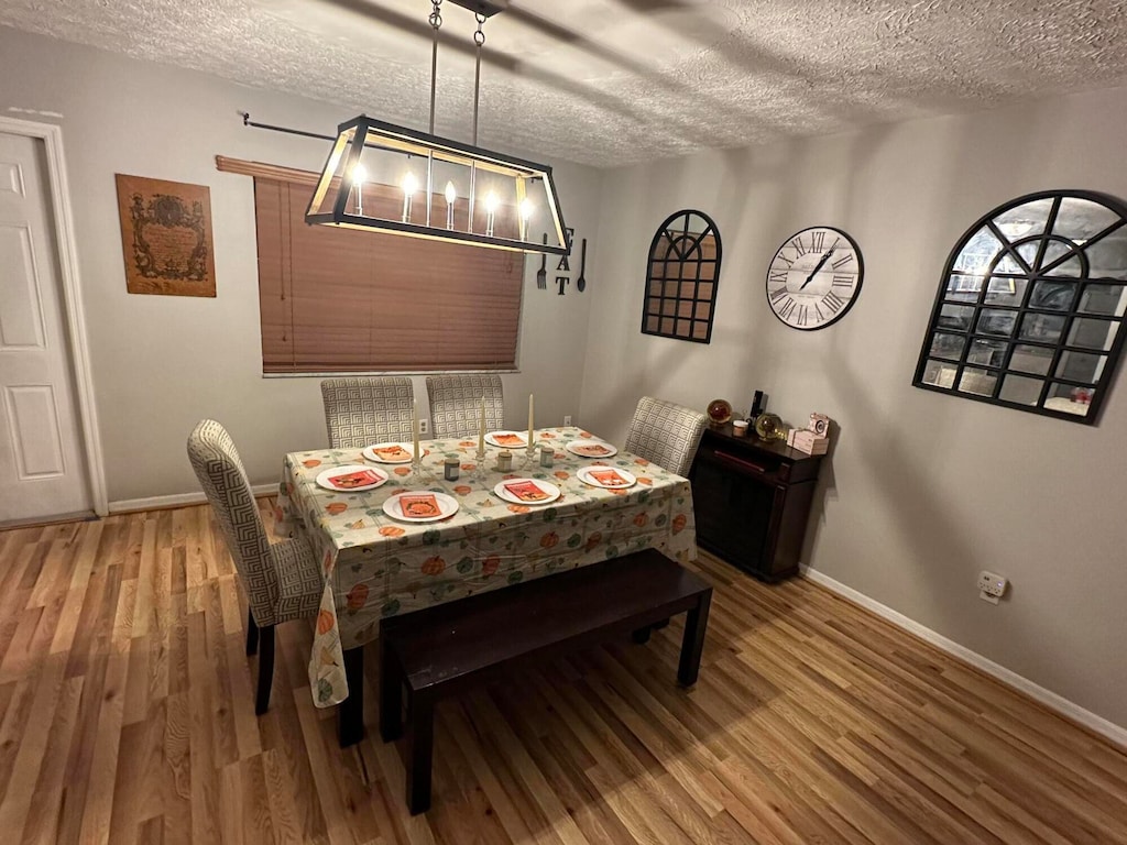 dining space with hardwood / wood-style floors and a textured ceiling