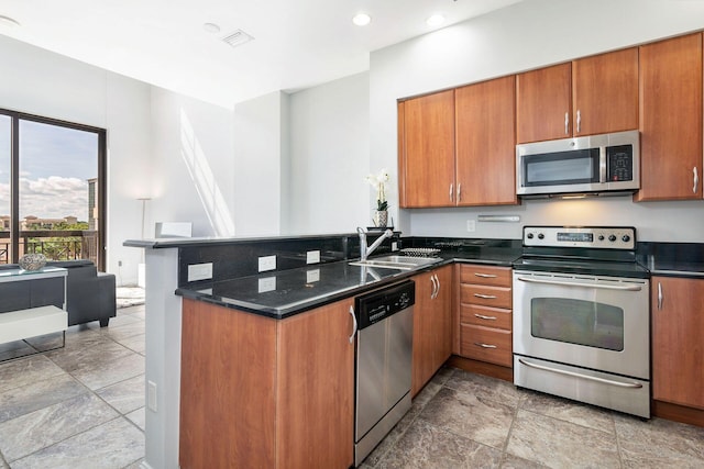 kitchen featuring dark stone countertops, appliances with stainless steel finishes, sink, and kitchen peninsula