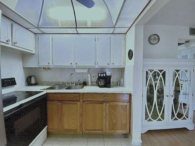 kitchen featuring decorative backsplash, white electric range oven, sink, and light tile patterned floors