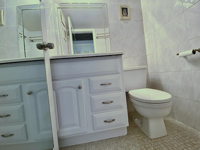 bathroom featuring tile walls, vanity, and toilet