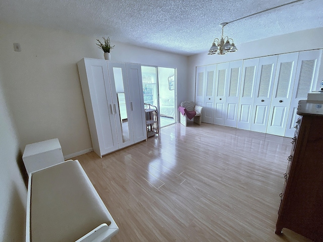 interior space featuring a notable chandelier, a textured ceiling, and light wood-type flooring