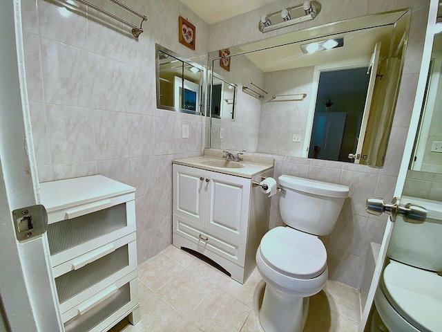 bathroom with toilet, vanity, and tile walls