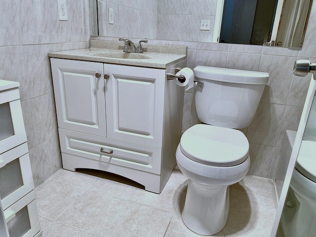 bathroom featuring vanity, toilet, tile patterned floors, and tile walls