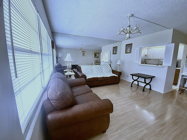 living room featuring light hardwood / wood-style floors, a notable chandelier, and a textured ceiling