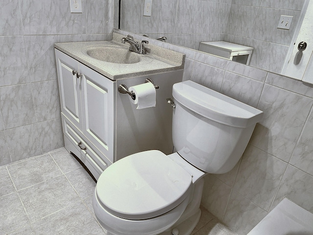 bathroom with toilet, vanity, and tile walls