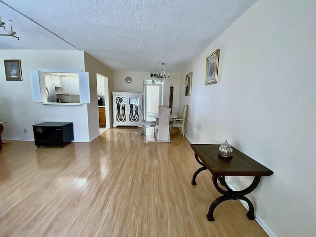 living room featuring an inviting chandelier, a textured ceiling, and light wood-type flooring