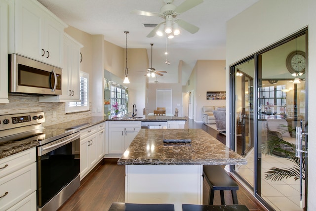 kitchen featuring white cabinetry, a breakfast bar, appliances with stainless steel finishes, dark hardwood / wood-style floors, and a kitchen island