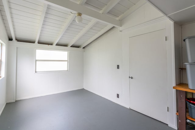 empty room with vaulted ceiling with beams