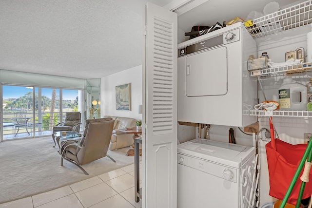 laundry room with stacked washer / drying machine, light tile patterned flooring, and a textured ceiling