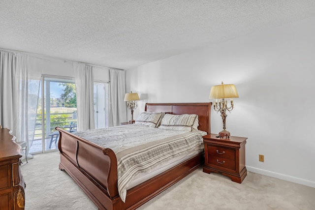 bedroom featuring access to outside, light colored carpet, and a textured ceiling