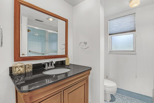 bathroom featuring tile patterned floors, a shower with door, vanity, and toilet