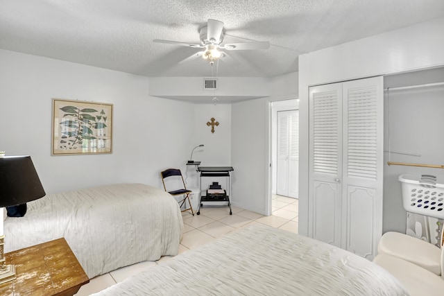 bedroom with ceiling fan, a closet, light tile patterned floors, and a textured ceiling