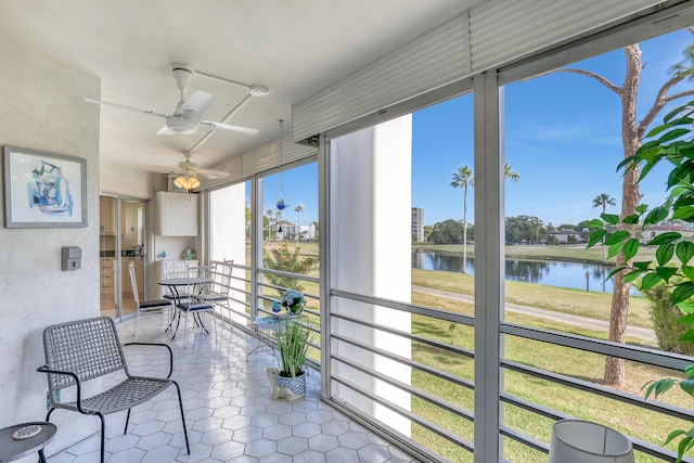 sunroom featuring a water view and ceiling fan