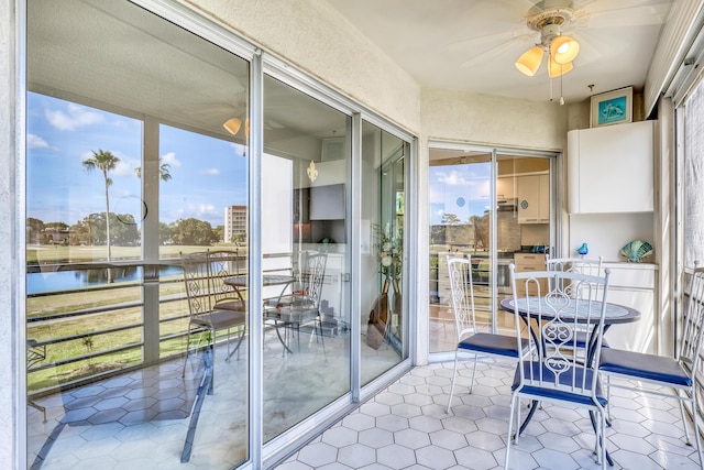 sunroom / solarium featuring ceiling fan, a water view, and a healthy amount of sunlight