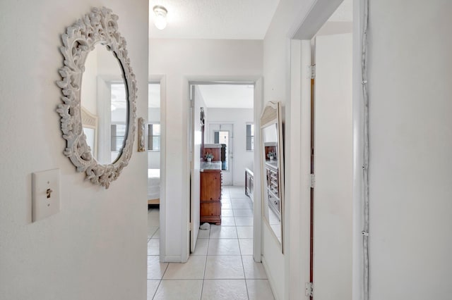 hall with a textured ceiling and light tile patterned floors