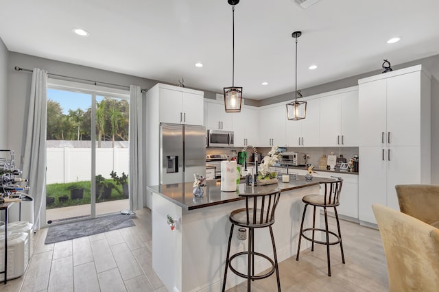 kitchen featuring white cabinets, backsplash, light hardwood / wood-style flooring, decorative light fixtures, and stainless steel appliances