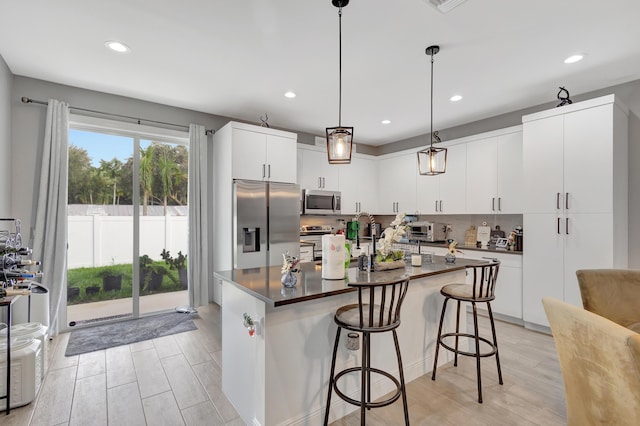 166 Neva Dr, West Palm Beach, FL 33415 - kitchen with stainless steel appliances, dark countertops, a kitchen breakfast bar, backsplash, and hanging light fixtures