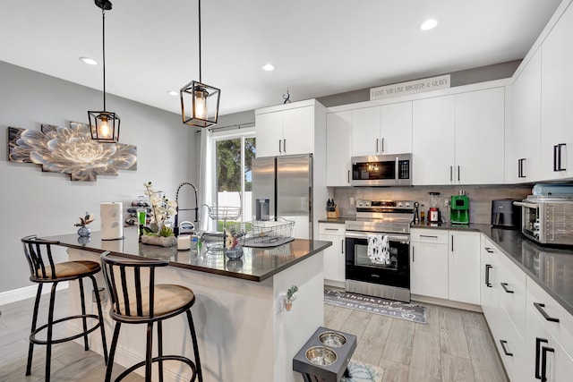 kitchen featuring white cabinetry, a kitchen bar, stainless steel appliances, and light hardwood / wood-style floors