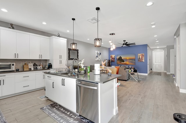 kitchen featuring sink, pendant lighting, stainless steel dishwasher, light hardwood / wood-style flooring, and a kitchen island with sink