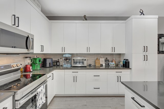 166 Neva Dr, West Palm Beach, FL 33415 - kitchen featuring stainless steel appliances, dark countertops, white cabinetry, and tasteful backsplash