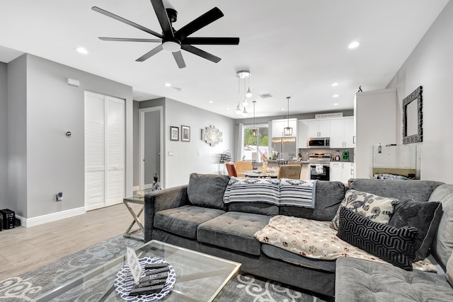 living room with light hardwood / wood-style flooring and ceiling fan