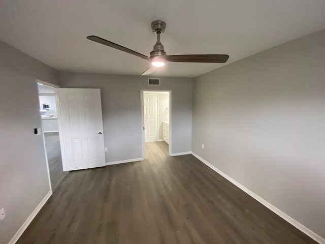 unfurnished bedroom featuring ceiling fan, dark hardwood / wood-style flooring, and ensuite bath