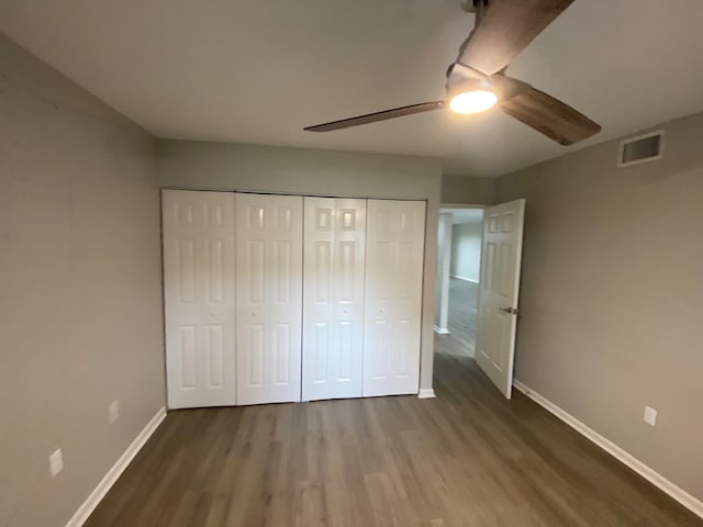 unfurnished bedroom with dark hardwood / wood-style flooring, a closet, and ceiling fan