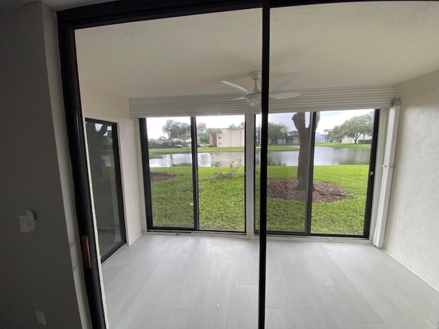 unfurnished sunroom featuring a water view, ceiling fan, and a healthy amount of sunlight