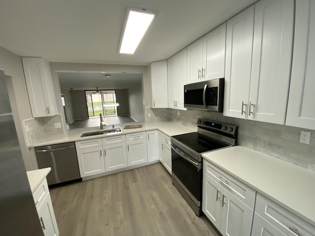 15324 Lakes Of Delray Blvd Unit 104, Delray Beach, FL 33484 - kitchen with stainless steel appliances, a sink, light wood-style flooring, and white cabinetry
