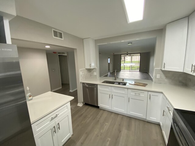15324 Lakes Of Delray Blvd Unit 104, Delray Beach, FL 33484 - kitchen featuring appliances with stainless steel finishes, a sink, light wood-style flooring, light countertops, and white cabinetry