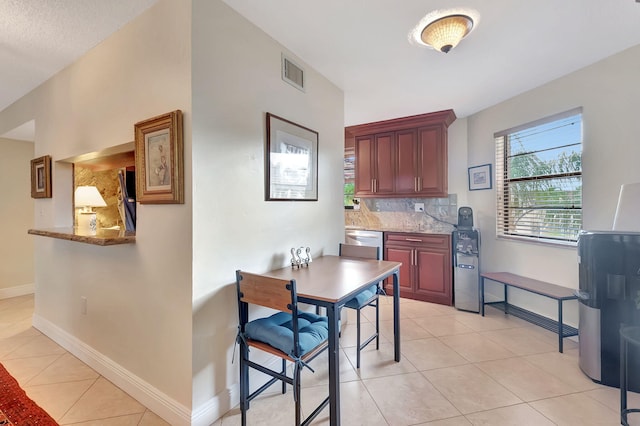 kitchen with decorative backsplash, light tile patterned flooring, light stone counters, and dishwasher