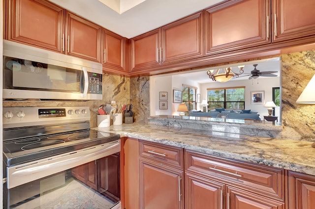 kitchen with light stone countertops, stainless steel appliances, tasteful backsplash, and ceiling fan