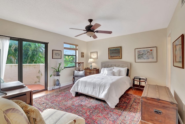 bedroom featuring ceiling fan, access to exterior, a textured ceiling, and hardwood / wood-style floors