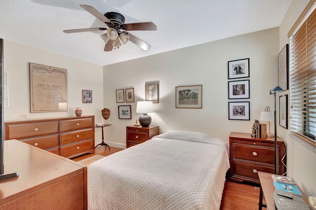 bedroom featuring light hardwood / wood-style flooring, a textured ceiling, and ceiling fan