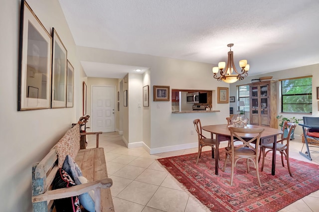 dining area with a notable chandelier, a textured ceiling, and light tile patterned floors