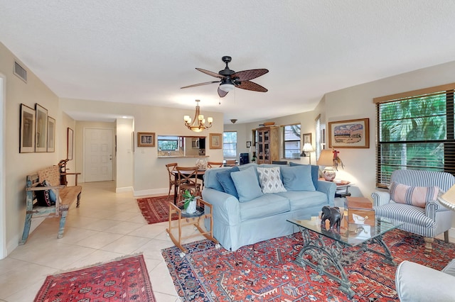 living room featuring a textured ceiling, light tile patterned floors, plenty of natural light, and ceiling fan with notable chandelier