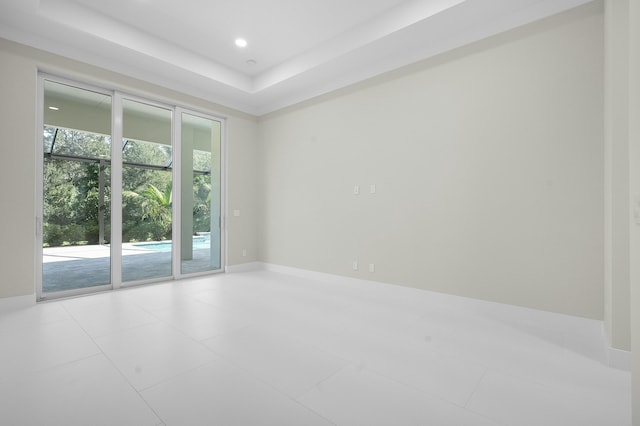 empty room with a tray ceiling and light tile patterned floors