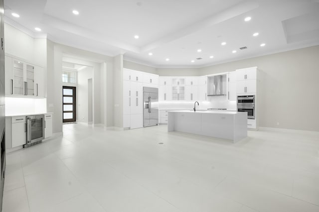 kitchen with wine cooler, a center island with sink, a tray ceiling, white cabinetry, and stainless steel appliances