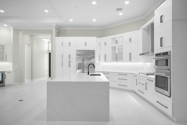 kitchen with a kitchen island with sink, sink, stainless steel appliances, and white cabinetry