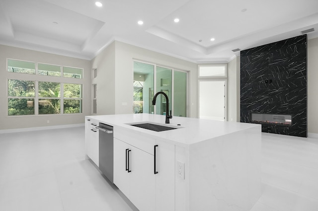 kitchen featuring dishwasher, white cabinetry, sink, a kitchen island with sink, and a tray ceiling