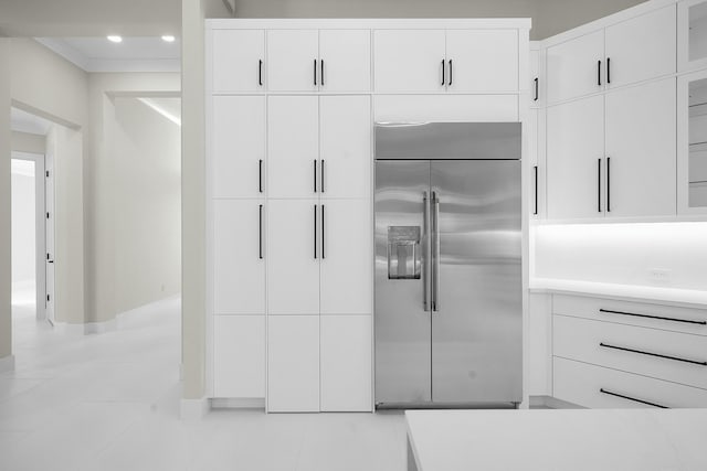 kitchen with light tile patterned floors, built in refrigerator, and white cabinetry