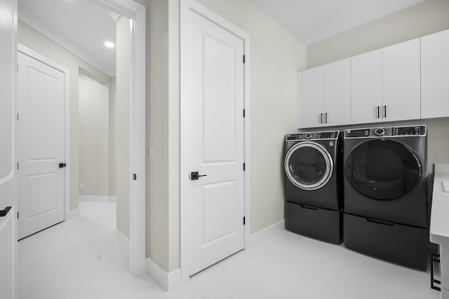 clothes washing area featuring light tile patterned flooring, separate washer and dryer, and cabinets