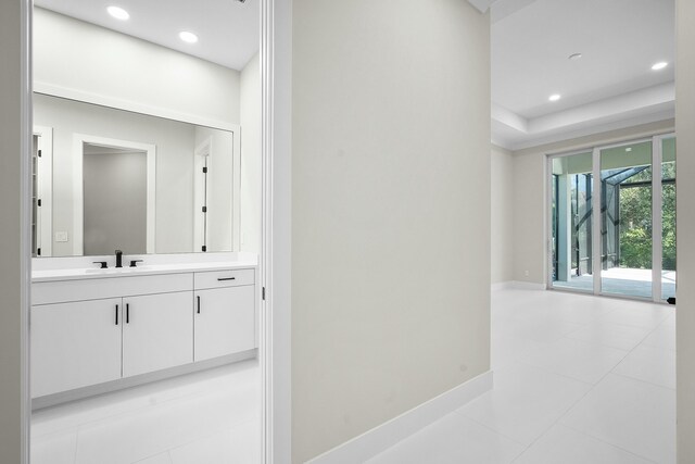 hall with light tile patterned floors, a tray ceiling, and sink