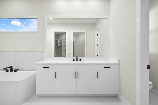 bathroom featuring a washtub, toilet, vanity, and tile patterned flooring