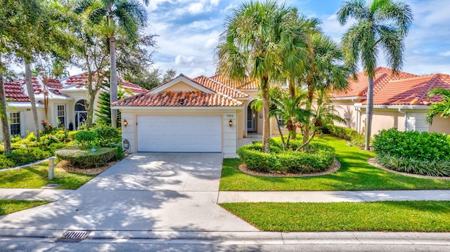 mediterranean / spanish home with an attached garage, a tiled roof, driveway, and stucco siding