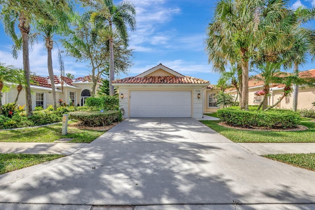 mediterranean / spanish home featuring an attached garage, stucco siding, driveway, and a tiled roof