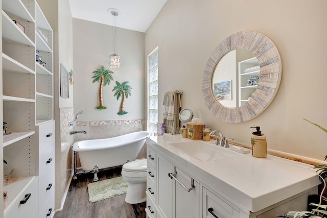 full bathroom featuring wood finished floors, vanity, a freestanding bath, lofted ceiling, and tile walls