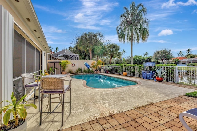 view of pool with a patio, a water view, and glass enclosure