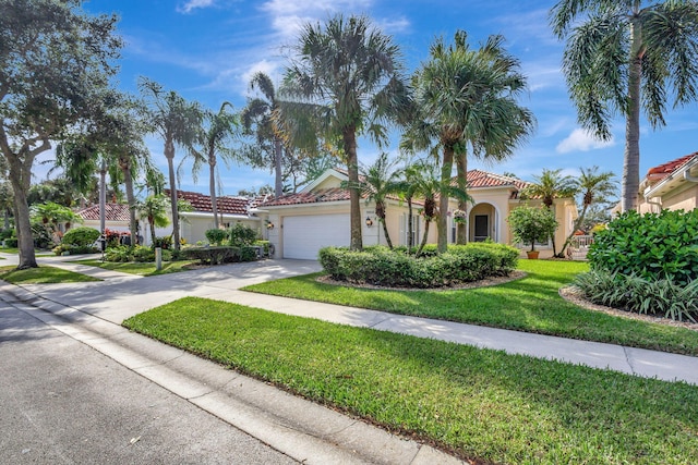mediterranean / spanish house featuring stucco siding, concrete driveway, a front yard, a garage, and a tiled roof