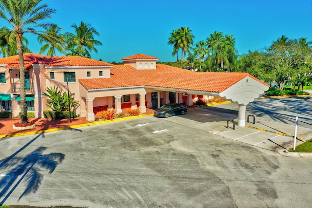 view of front facade with a tile roof, stucco siding, and a parking lot